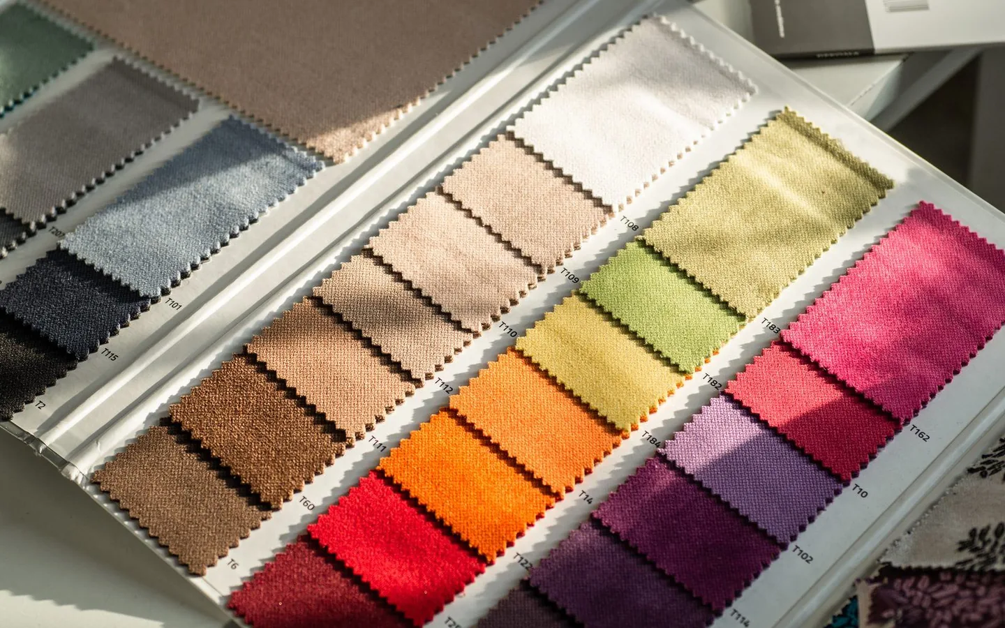 An open swatch book of fabric samples, each shade carrying its own reference code
